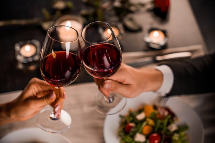 Les 7 meilleures destinations pour une Saint-Valentin inoubliable où aller pour un séjour à la saint-valentin ? couple qui trinque avec 2 verres de vin rouge.